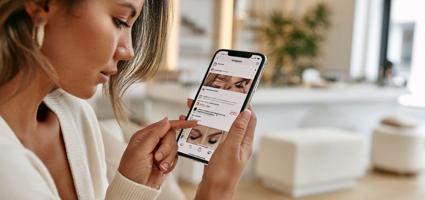 Lash artist scrolling through lash captions for Instagram on her phone while relaxing in a modern salon