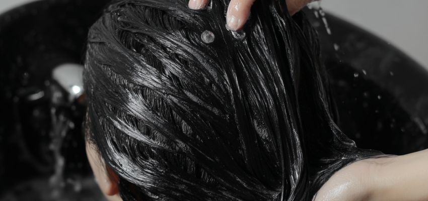 The woman is rinsing blackening shampoo out of her hair.