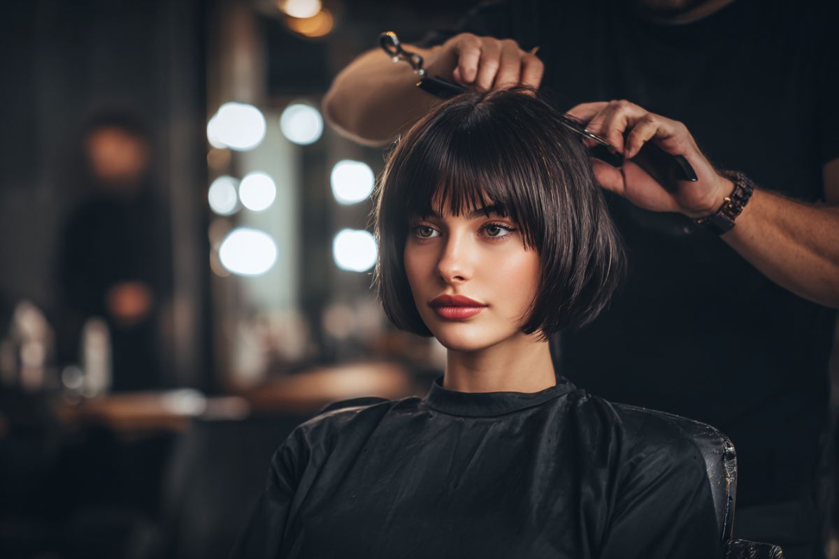 The woman is trying on a fringe haircut.
