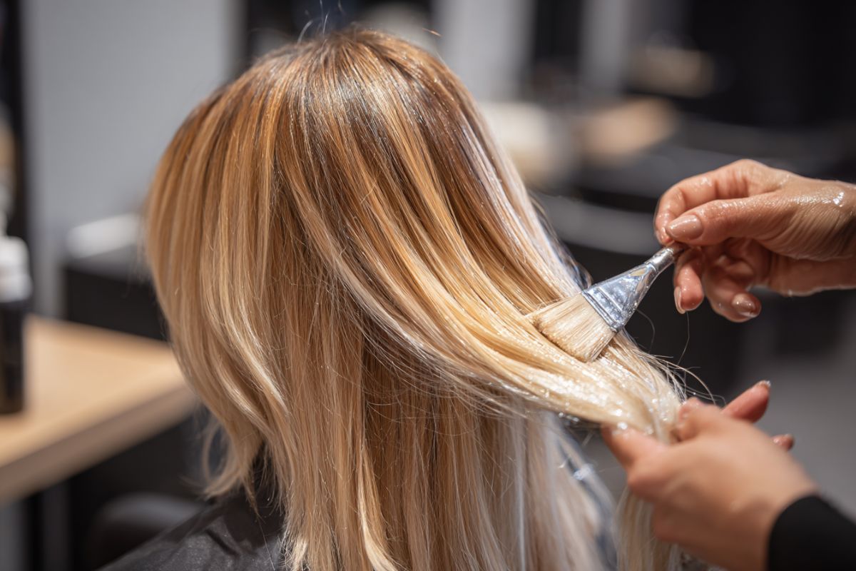 The hair colorist applies hair toner to her client's hair.