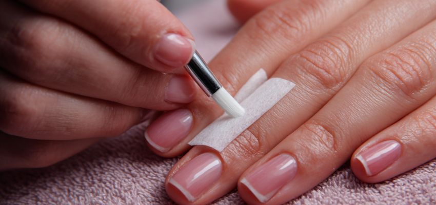 Professional applying base coat during nail prep steps