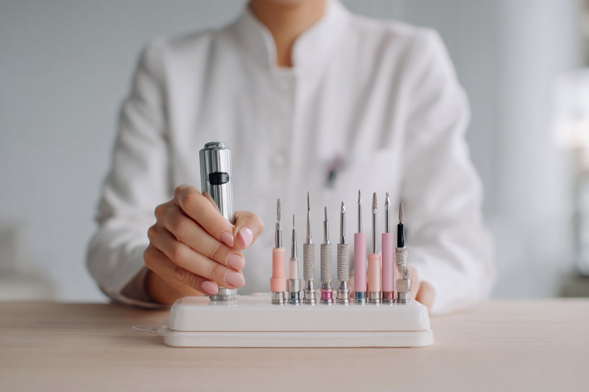 Professional presenting a full set of nail drill bits with an electric nail drill as different nail drill bits explained