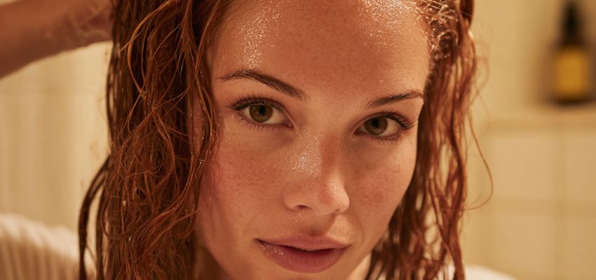 Close-up of woman with wet copper red hair in shower, showing natural hair color before toning - relevant to does toner damage hair discussions